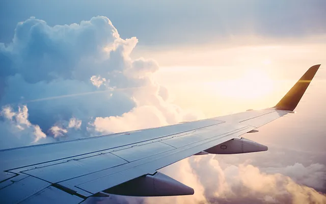 Airplane wing with the sun in the distance