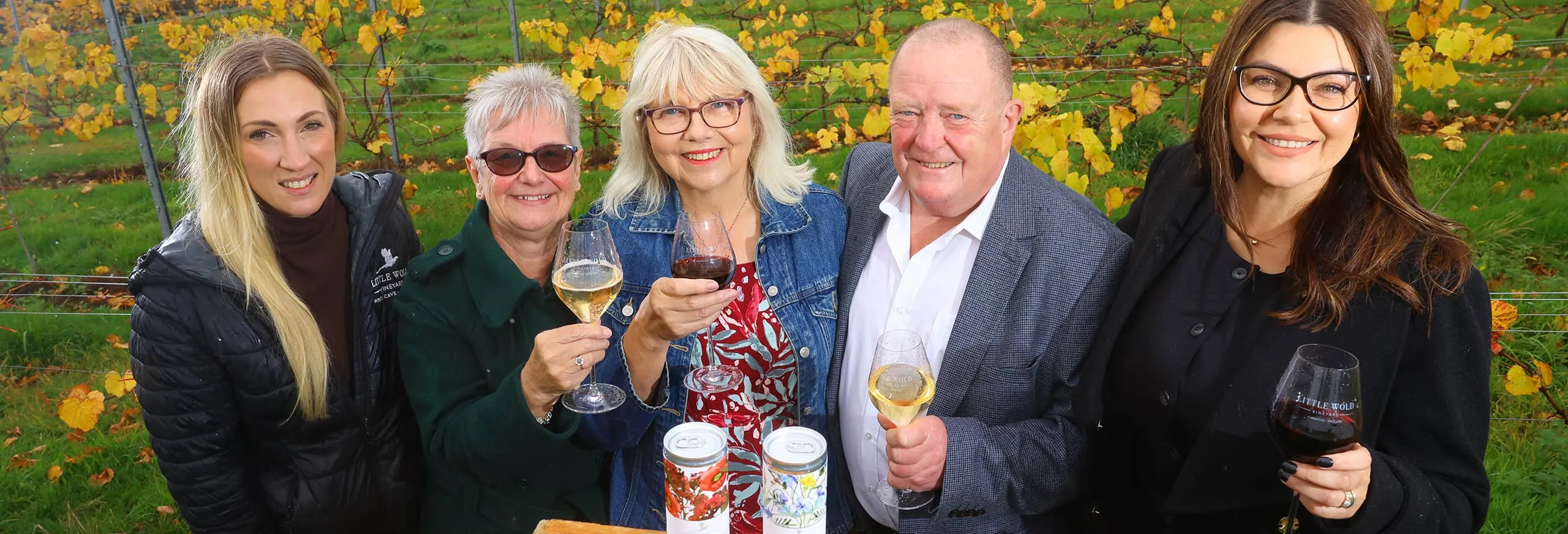 A group of people smiling holding glasses of wine