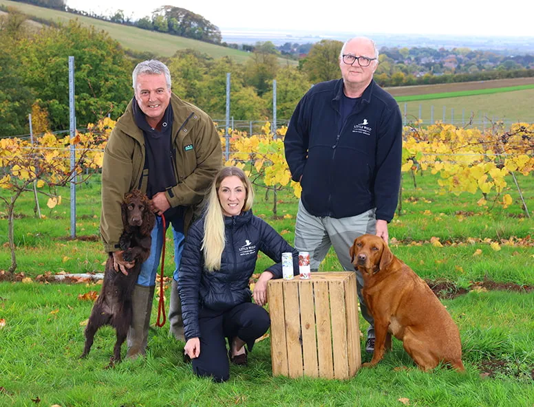 A group of people and two dogs smiling in the countryside