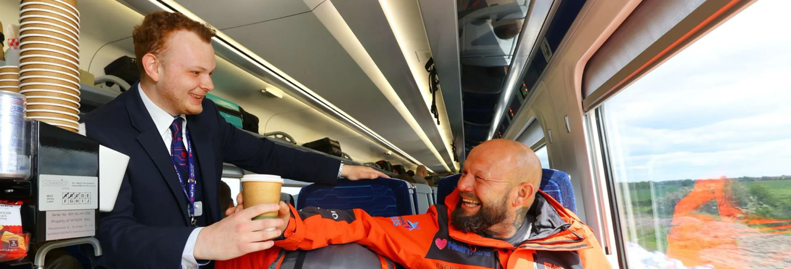 A man being served a hot drink from the at seat trolley service onboard a Hull Trains service